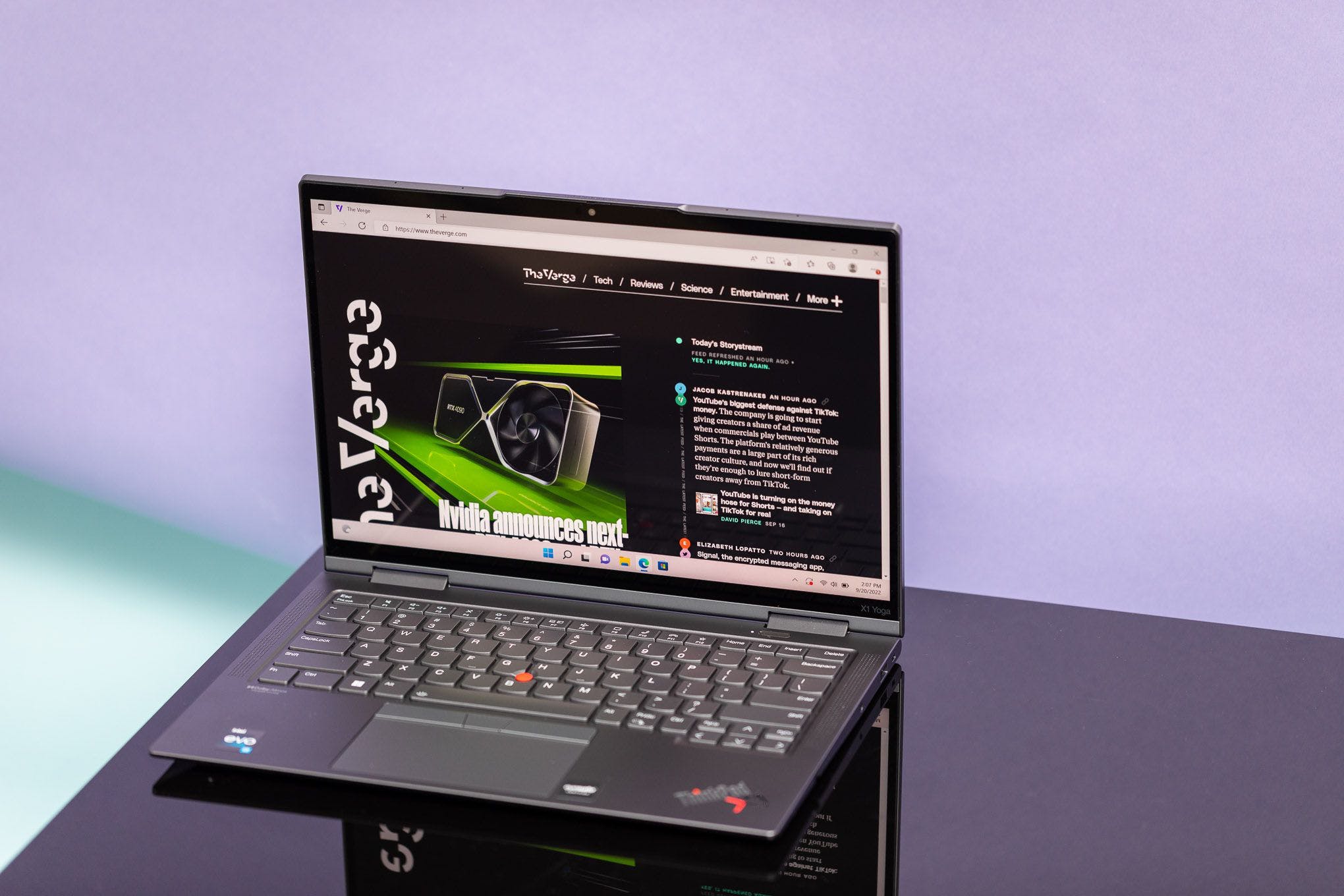 The Lenovo ThinkPad X1 Yoga Gen 7 on a black table seen from above, displaying The Verge homepage.