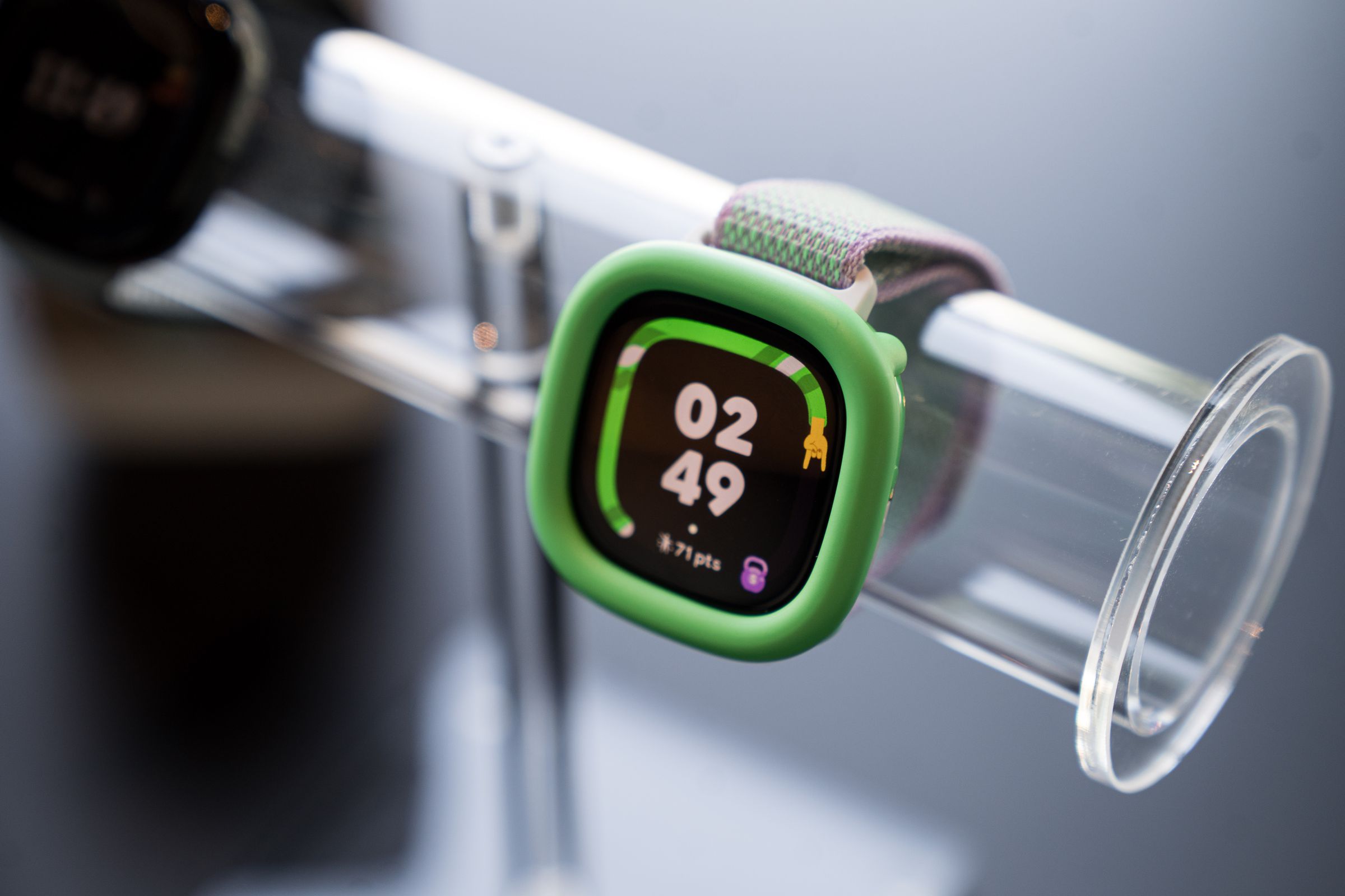 Close-up of the Fitbit Ace LTE in the Spicy Pebble variant with a neon green bumper.