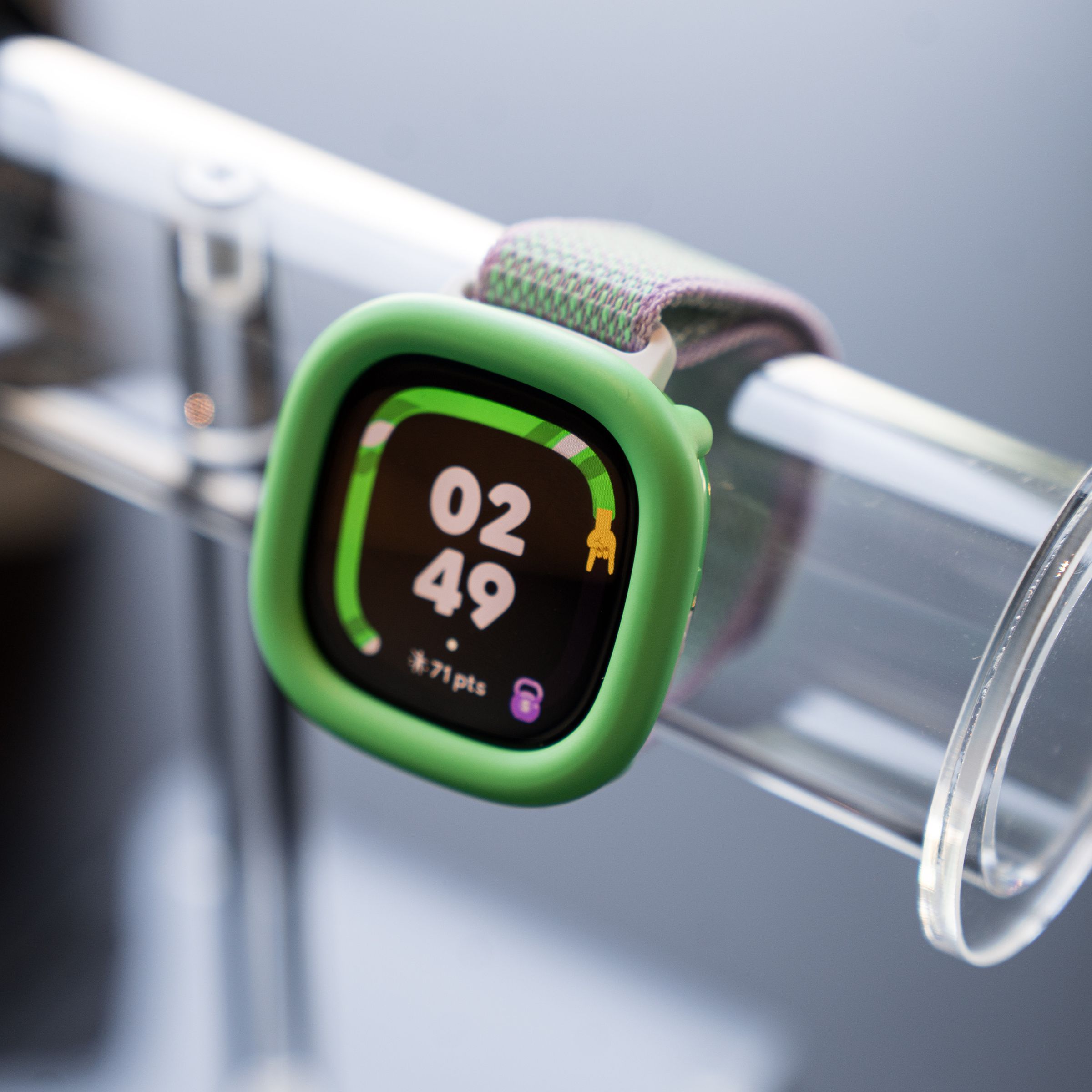 Close-up of the Fitbit Ace LTE in the Spicy Pebble variant with a neon green bumper.